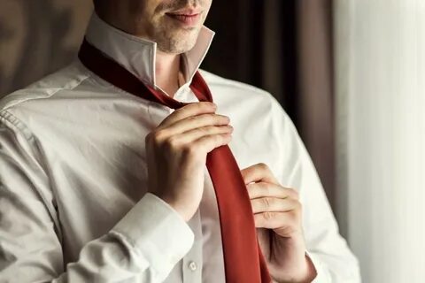 Мужчина одевает галстук